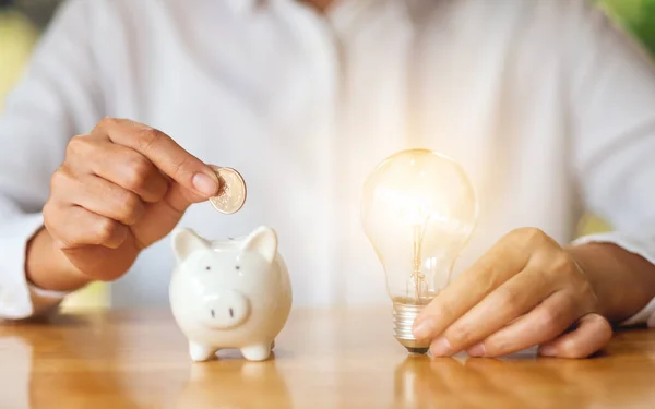 Woman Holding Light Bulb While Putting Coins Piggy Bank Saving — Fotografia de Stock