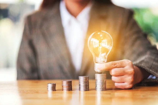 Empresária Segurando Colocando Lâmpada Pilha Moedas Mesa Para Economizar Energia — Fotografia de Stock