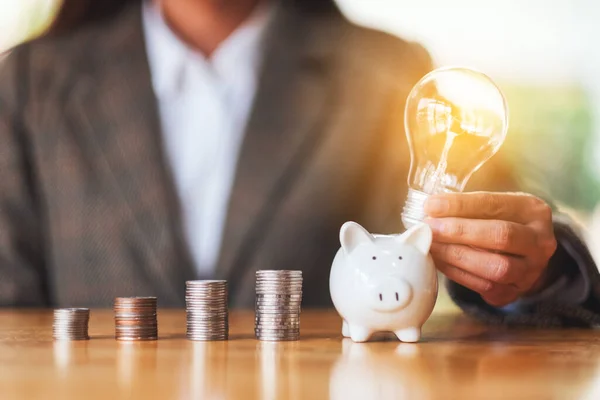 Businesswoman Putting Light Bulb Piggy Bank Coins Stack Table Saving — Fotografia de Stock