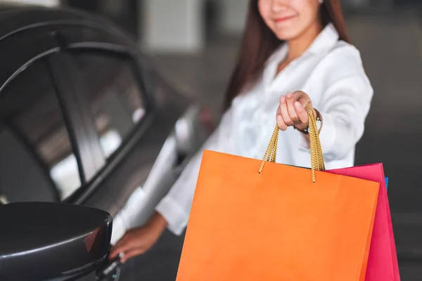 在商场停车场打开车门时 一个漂亮女人拿着购物袋并展示购物袋的照片 — 图库照片