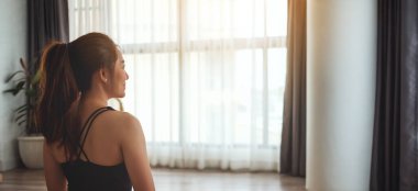 Evde antrenman yapmaya hazırlanan Asyalı güzel bir kadının arka plan görüntüsü.