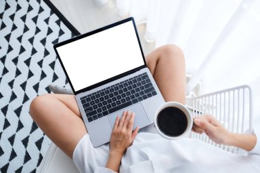 Üst görüntüde dizüstü bilgisayarın dokunmatik dokunmatik dokunmatik dokunmatik dokunmatik dokunmatik dokunmatik bir kadın evde bir yatak odasında oturup kahve içerken görüntüsü var.