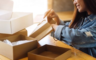 Güzel bir Asyalı kadının teslimat ve online alışveriş konsepti için evdeki alışveriş çantasının içini açıp içine baktığı yakın plan.