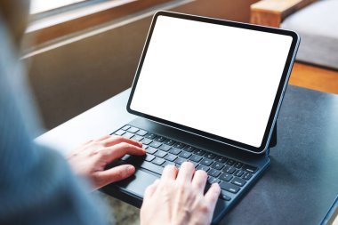 Tablet klavyesinde boş beyaz masaüstü ekranı bir bilgisayar bilgisayarı olarak kullanan ve yazan bir kadının görüntüsü