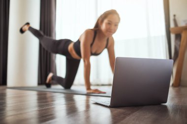 A beautiful young asian woman watching online workout tutorials on laptop at home