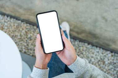 Boş beyaz masaüstü ekran ile cep telefonu tutan bir kadının en üst görünüm görüntüsü 