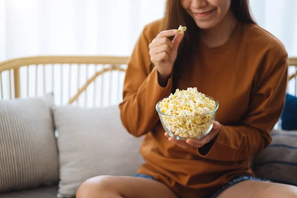 一个漂亮的年轻女子坐在沙发上拿着和吃着爆米花的近照 — 图库照片