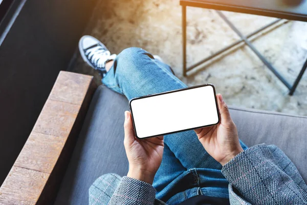 Beyaz masaüstü ekranlı siyah bir cep telefonu tutan bir kadının üst görünüm görüntüsü
