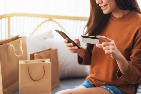 一个漂亮的年轻女子用手机和信用卡在网上购物的照片 — 图库照片