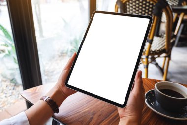 Masasında kahve fincanı olan siyah tabletli beyaz ekranlı bir kadının görüntüsü.