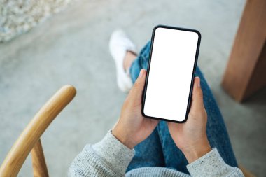 Boş beyaz masaüstü ekran ile cep telefonu tutan bir kadının en üst görünüm görüntüsü 