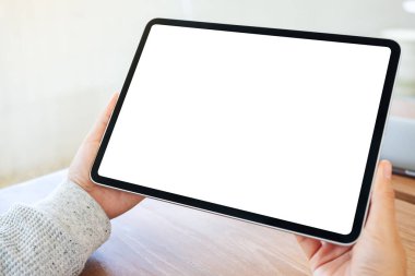 Ahşap masada beyaz ekranlı siyah tabletli bir kadının görüntüsü.