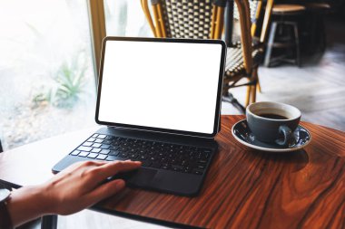 Tablet touchpad 'e dokunan bir kadının resmi. Masasında kahve fincanı olan bir bilgisayar ekranı.