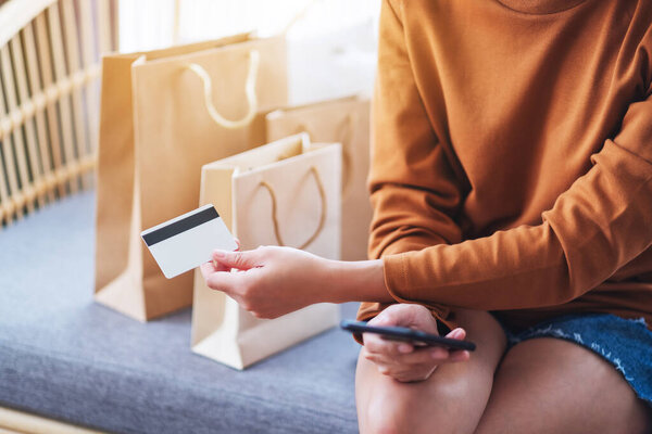 Closeup image of a young woman using mobile phone and credit card for online shopping