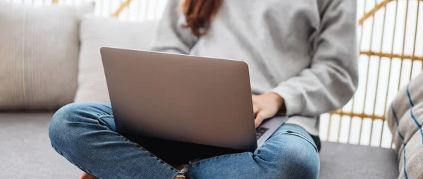 一位年轻女性坐在沙发上使用和使用笔记本电脑的图片 图库图片