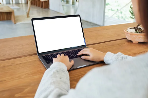 一个女人在笔记本电脑键盘上用空白白屏在木制桌子上打字的模特儿 免版税图库照片