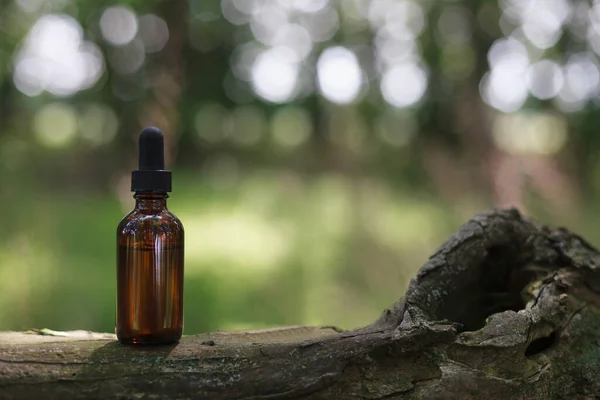 Brown bottle with herbal oil on old tree. Alternative medicine, place for text.