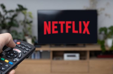 Poznan Polonya - 21 Haziran 2021: TV uzaktan kumandası ve arka planda Netflix logosu. Netflix, canlı film ve televizyon dizilerinin küresel sağlayıcısıdır..