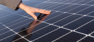 Kadın elinin ve güneş panellerinin yakın çekimi. Kavram: yenilenebilir enerji, teknoloji, elektrik. Boşluğu kopyala, web pankartı için resim.