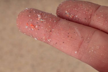Close-up of microplastics lay on finger of human being. Small plastic pellets on finger. Micro plastic, problem. clipart