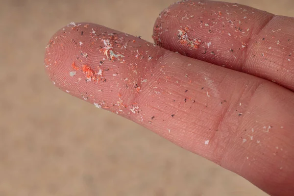 Close-up of microplastics lay on finger of human being. Small plastic pellets on finger. Micro plastic, problem.