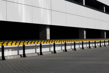Sarı ve siyah korkuluklar binanın dışında, otoparkta..