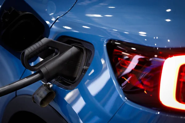 Loading energy of an electric blue car. Charging power to electric vehicle EV car, close-up.