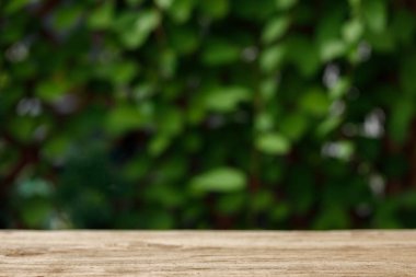 Boş ahşap masa üstü, bulanık park yeşil arka plan ışık saçar. Ürünün görüntülenmesi veya montajı için model.