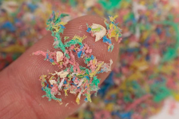 Small plastic pellets on the finger. Close-up of micro plastic as environmental pollution.