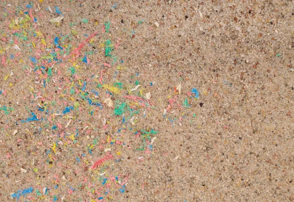 Micro plastic in sand on beach, colorful plastic particles. Close-up.