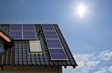 Part of the roof is covered with panels, blue clear skies. Text space. Blue solar panels .