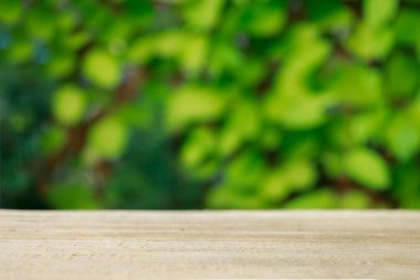 Wood table top on shiny bokeh green background. Blurred background of green park in summer.