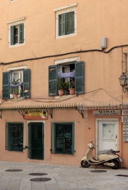 Korfu, Yunanistan. 02 Eylül 2022: Eski Korfu kasabasındaki tipik dar bir caddenin manzarası. Park etmiş scooter, motosiklet.