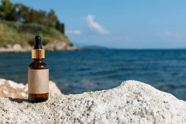 A mockup for a cosmetic product in a dropper. Bottle with gold cap and dropper on the background of an exotic beach. Medicinal preparation , empty label.