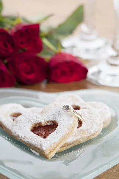 Gold engagement ring and shortbread hearts — Stock Photo, Image