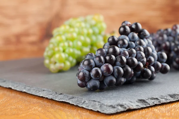 Grappoli di uva blu e verde su tavola di ardesia — Foto Stock