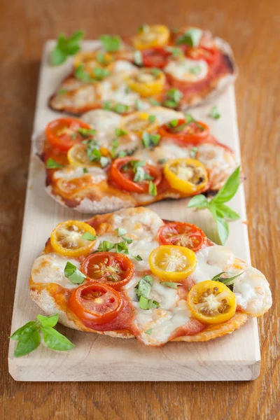 Mini pizzas à la mozzarella, tomates cerises et basilic — Photo