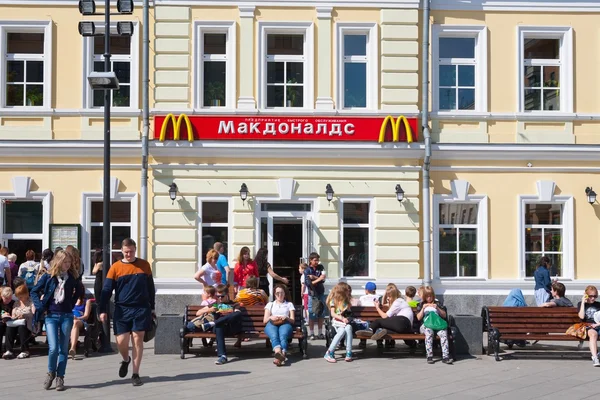 Personas sentadas en bancos cerca del edificio del restaurante McDonald 's — Foto de Stock