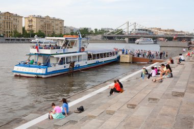 nehir kıyısındaki oturan insanlar. arka planda nehir gemisi