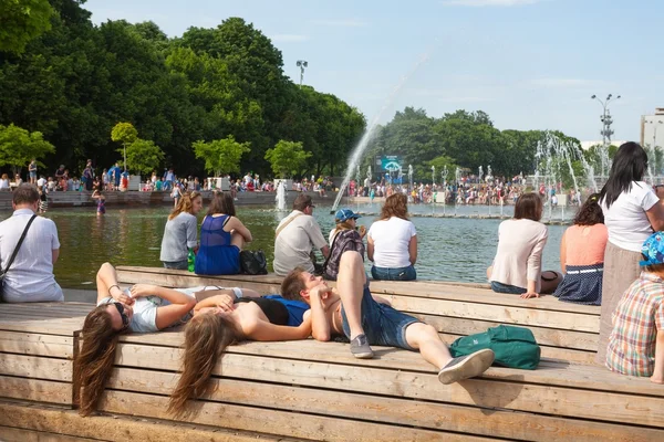 Persone sedute e distese vicino al laghetto fontana — Foto Stock