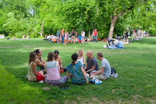 People talking and sitting on lawn — Stock Photo, Image