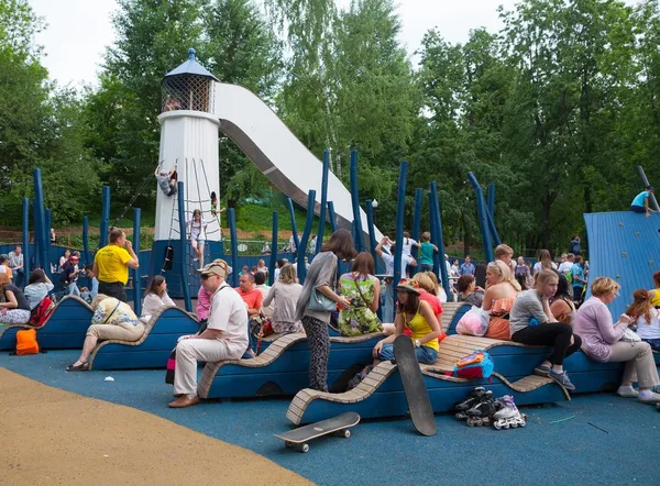 Enfants et adultes se reposant sur l'aire de jeux — Photo