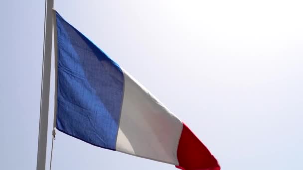 Французький прапор пурхає на блакитне небо в повільному русі. — стокове відео