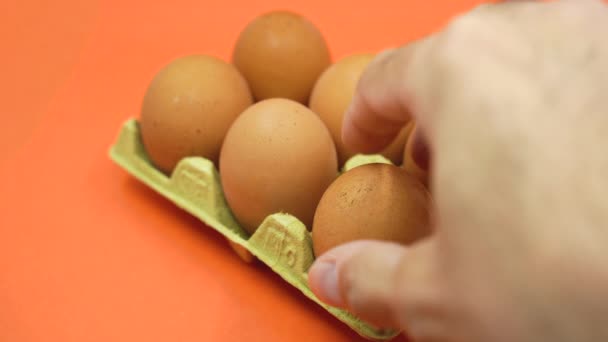 Рука Видаляє Яйце Відкритої Яєчної Коробки Помаранчевому Фоні Концепція Зменшення — стокове відео
