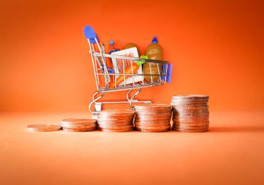 Inflation, growth of Groceries sales, growth of market basket or consumer price index concept. Coins in the form of an ascending graph with Shopping cart with groceries