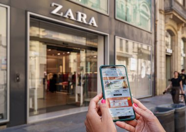 Barcelona, Spain. August 2022: Woman holding a smartphone with the Shein app on the screen and a Zara store in the background