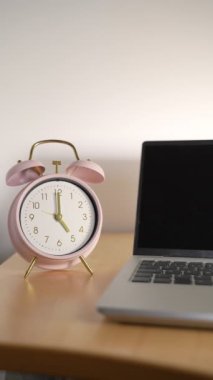 Vertical view of a Clock marking 5 pm and a laptop with the lid closed. Concepts such as quiet quitting, coffee break or taking a break at work
