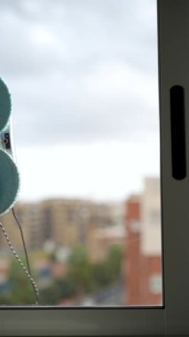 Bir robot pencere temizleyicisi. Robot elektrikli süpürge kirli bir pencereyi temizliyor. Pencereleri silmek için akıllı robotlar, ev için bir asistan. Oda temizliği, temizlik ve pencereleri cilalama kavramı.