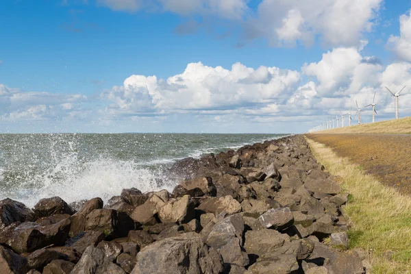 Vågor nära en holländsk vågbrytare med windturbines — Stockfoto