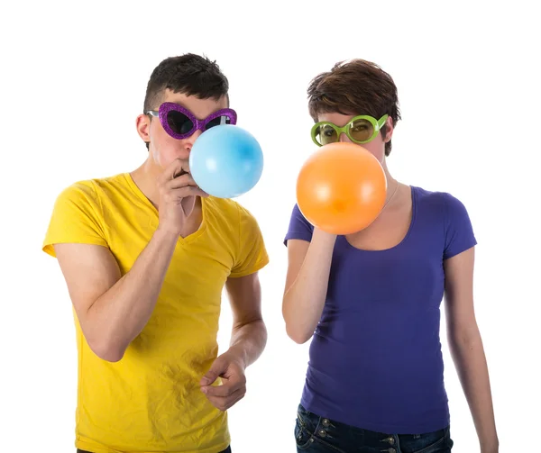 Mężczyzna i kobieta z okulary, dmuchanie balonów — Zdjęcie stockowe